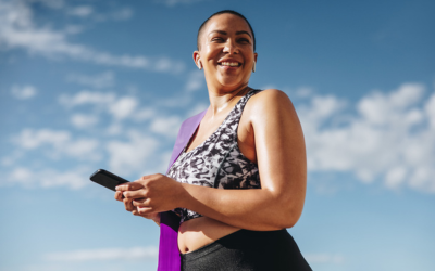 Plus size woman on phone outside with yoga mat.